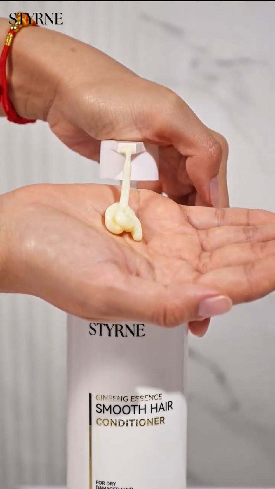 Person applying STYRNE Smooth Hair Conditioner to their hand with a bottle in the background.