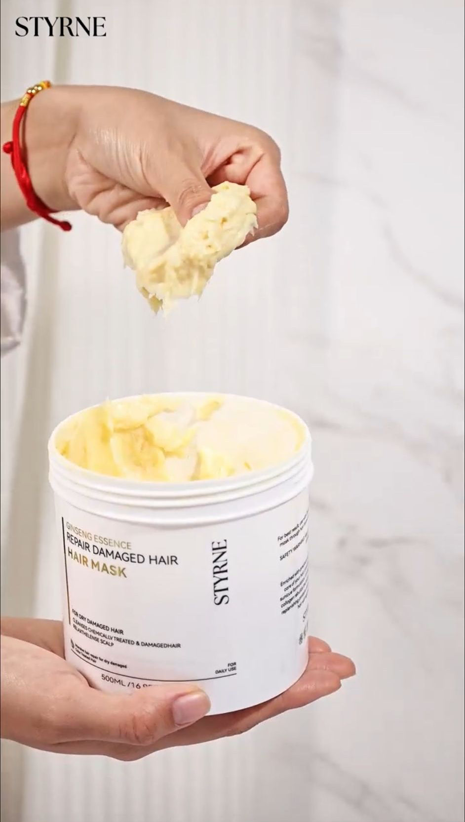 Person holding a container of STYRNE hair product with a white background
