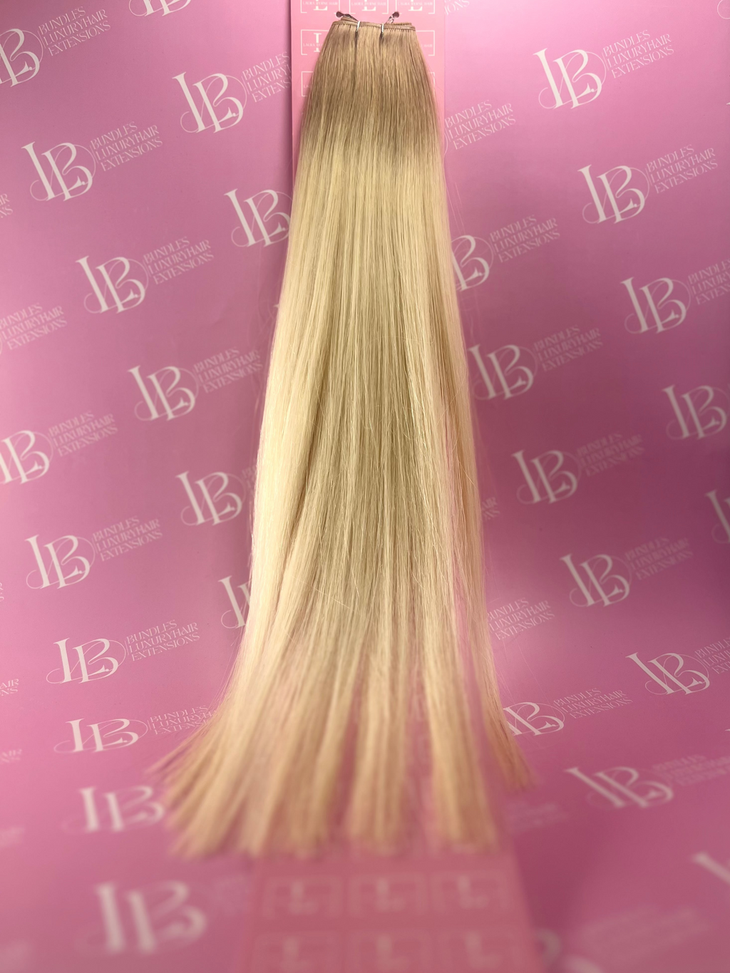 Blonde hair extensions on a pink background with 'IB' branding.