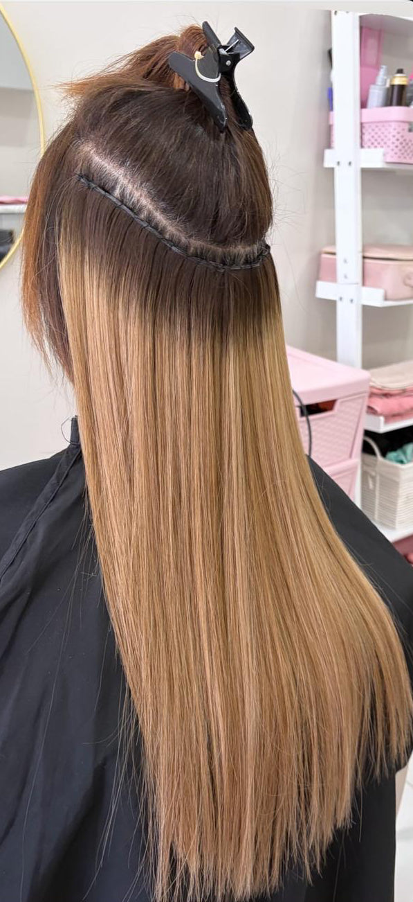 Person with hair styled in a salon setting, wearing a black cape.