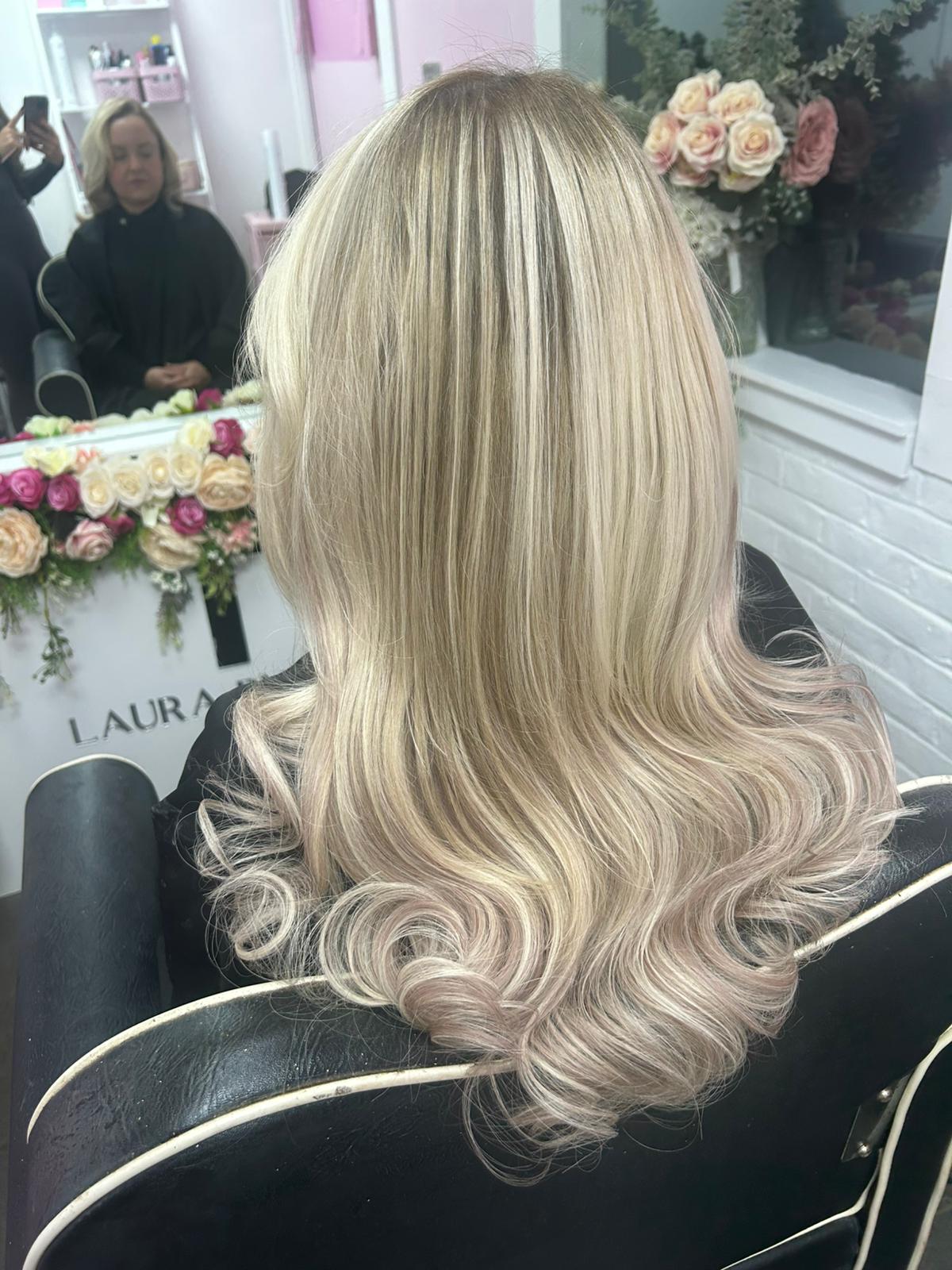 Blonde hair styled in a salon setting with floral decorations.